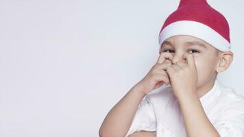 retrato do uma criança de seis anos Garoto contra a branco fundo. a comemorar Natal. 6-7 ano velho criança com santa chapéu. foto