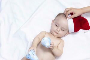 9 mês bebê Garoto com santa claus chapéu. Natal manhã. pequeno criança jogando. foto