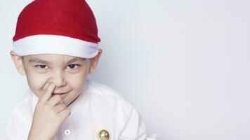 retrato do uma criança de seis anos Garoto contra a branco fundo. a comemorar Natal. 6-7 ano velho criança com santa chapéu. foto