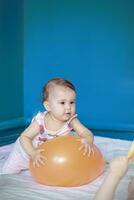 bebê jogando com uma balão. bebê menina fazendo dela diariamente Atividades. pequeno fofa menina Aprendendo para ficar de pé acima e andar. foto