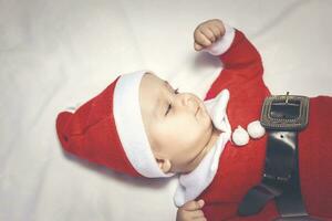 pequeno papai noel. 6-9 meses velho bebê Garoto dentro santa claus fantasia. alegre Natal foto