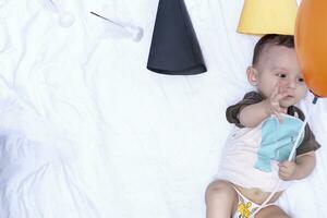 bebê jogando com uma balão. primeiro aniversário. bebê Garoto deitado às dele cama foto