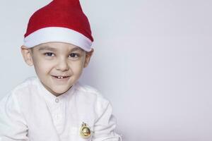 feliz pequeno Natal garoto. a comemorar Natal. 6-7 ano velho criança com santa chapéu. foto