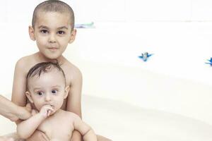 dois irmãos tendo água Diversão dentro banho foto