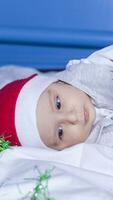 pequeno engraçado santa Garoto jogando com Natal ou Novo ano feriado festivo festão. 1 ano velho bebê Garoto dentro santa claus boné. foto