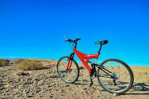 uma vermelho montanha bicicleta é estacionado em a deserto foto