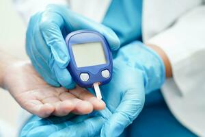 ásia médico usando digital glicose metro para Verifica amostra sangue açúcar nível para tratamento diabetes. foto