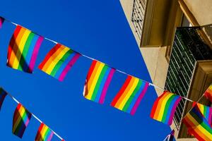 pequeno arco Iris bandeira contra a céu dentro uma espanhol cidade foto