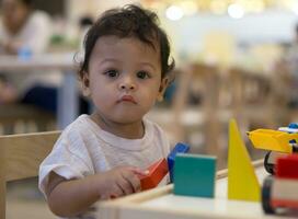 ásia criança pequena jogando com colorida de madeira brinquedo. foto