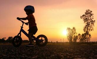 silhueta ásia criança primeiro dia jogar Saldo bicicleta. foto