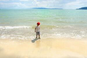 ásia Garoto jogando em a Tailândia mar e branco areia de praia foto
