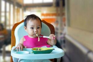 ásia menina 11 meses ano velho é comendo Comida. foto