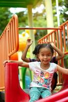 ásia menina é apreciar em uma Parque infantil equipamento dentro uma escola. foto