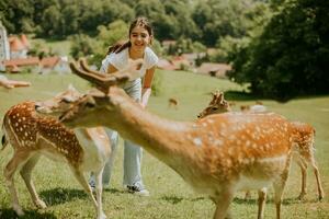 pequeno menina entre rena rebanho em a ensolarado dia foto