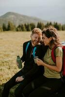 jovem casal relaxando em um capô de veículo de terreno na zona rural foto