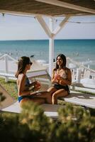 sorridente jovem mulheres dentro bikini desfrutando período de férias em a de praia foto