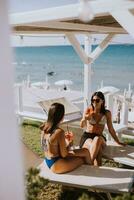 sorridente jovem mulheres dentro bikini desfrutando período de férias em a de praia foto