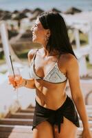 sorridente jovem mulher dentro bikini desfrutando período de férias em a de praia foto