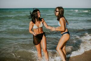 dois bonita jovem mulher tendo Diversão em a beira-mar foto