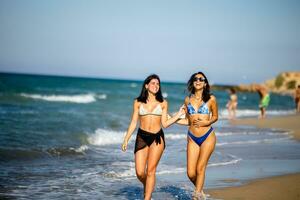 dois bonita jovem mulher tendo Diversão em a beira-mar foto