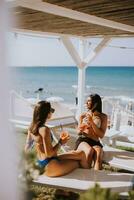 sorridente jovem mulheres dentro bikini desfrutando período de férias em a de praia foto