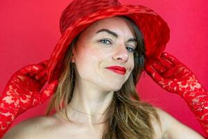 retrato do fofa jovem mulher vestindo chapéu e vermelho luvas em vermelho fundo foto