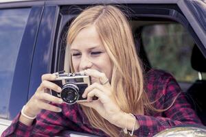 jovem loiro menina leva uma foto a partir de uma carro