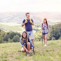 grupo do jovem caminhantes caminhando em direção a a horizonte sobre a montanha foto