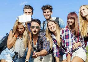 grupo do amigos levando uma auto retrato com selfie bastão foto