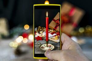 uma homem fotografias a mesa com Natal decorações com dele Smartphone foto