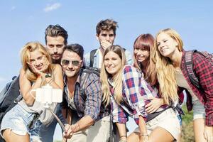 grupo do amigos levando uma auto retrato com selfie bastão foto