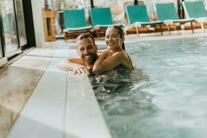 jovem casal relaxante dentro a interior natação piscina foto