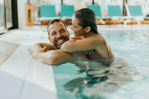 jovem casal relaxante dentro a interior natação piscina foto