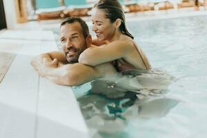 jovem casal relaxante dentro a interior natação piscina foto