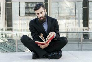 hipster jovem lendo um livro sentado ao ar livre foto