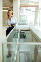 jovem mulher com caderno em pé dentro a moderno escritório corredor foto