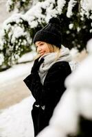 jovem mulher dentro caloroso roupas desfrutando dentro neve foto
