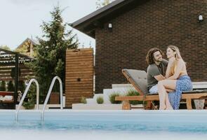 jovem casal relaxante de a natação piscina dentro a casa quintal foto