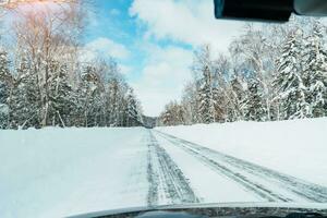 lindo neve estrada floresta Visão durante carro dirigindo dentro inverno temporada. inverno viagem, estrada viagem, aventura, explorando e período de férias conceitos foto