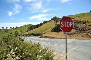 Pare tráfego placa às enrolamento estrada em topo do Colina dentro Austrália foto