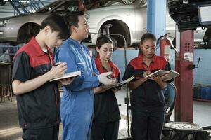 especialista palestra. masculino Supervisor engenheiro descrever automotivo suspensão fixação com mecânico trabalhador funcionários equipes para reparar trabalhos às carro serviço garagem e manutenção empregos dentro automóvel indústria. foto