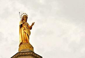 uma ouro estátua do Maria em topo do uma construção foto