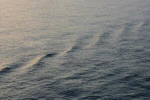 uma barco é Navegando através a oceano às pôr do sol foto
