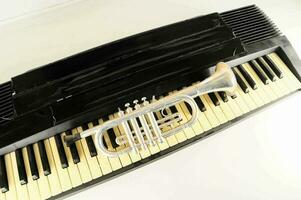 uma prata trompete em topo do uma piano teclado foto