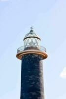 uma farol com uma Preto torre e uma branco luz foto