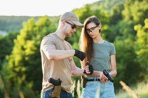 uma menina aprende para tiro uma pistola com a instrutor às a Treinamento terra foto