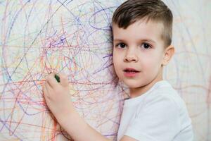 Garoto desenha em a parede com colori giz. a criança é acionado dentro criatividade às casa foto