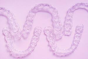 invisível dental dentes colchetes dente alinhadores em Rosa fundo. plástico suspensórios odontologia retentores para endireitar dentes. foto