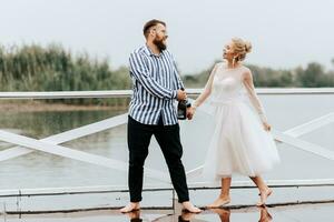 lindo somente casado dança descalço e ter Diversão em a cais de a água. foto