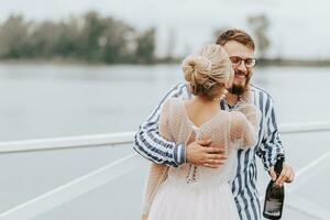 jovem recém-casados se beijando e abraçando em a cais de a água. foto